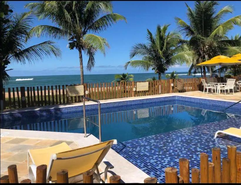 a swimming pool with a view of the ocean at Vilage beira-mar Itacimirim in Camaçari