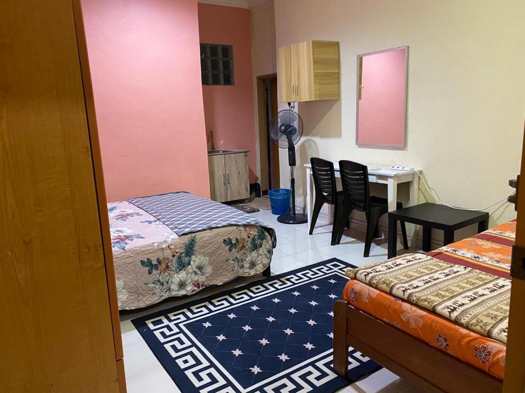 a room with two beds and a table and chairs at Bilik Harian Pengkalan Chepa in Pengkalan Cepa