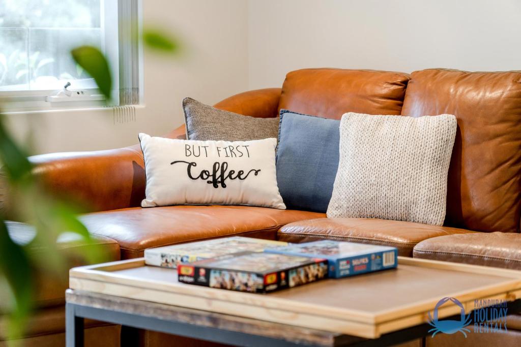 a brown leather couch with pillows on a coffee table at Tuart Heights in San Remo in Mandurah