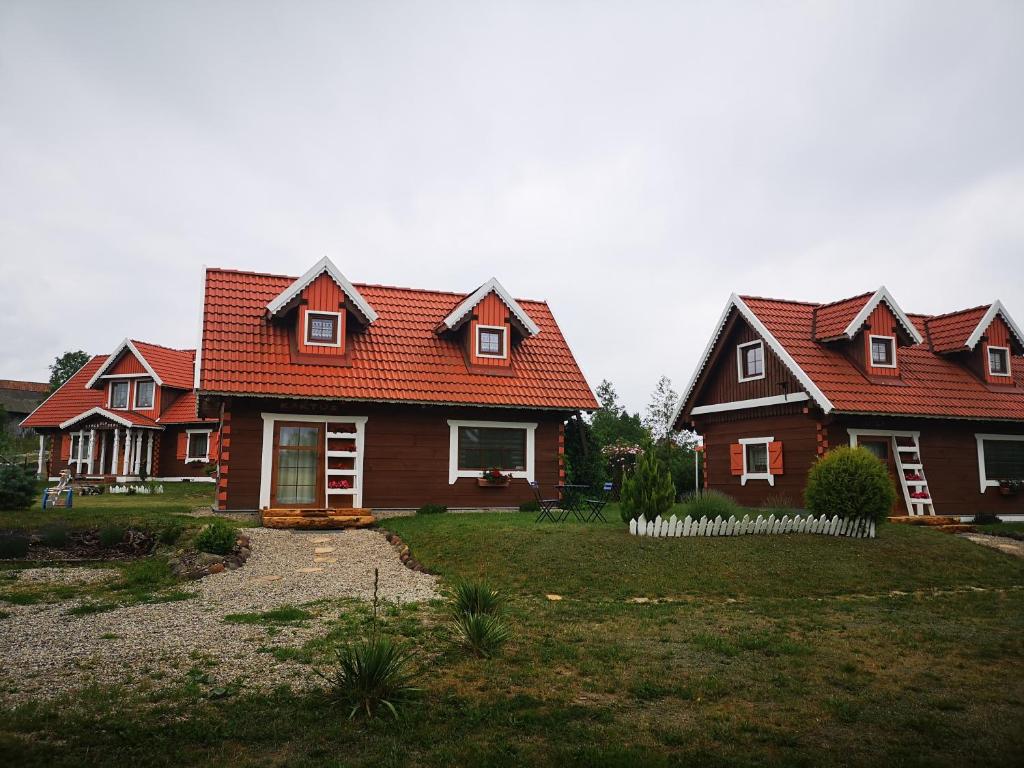 two houses with red roofs and a yard at Duży dom i domki z bala Mikołajki - Całoroczne in Mikołajki