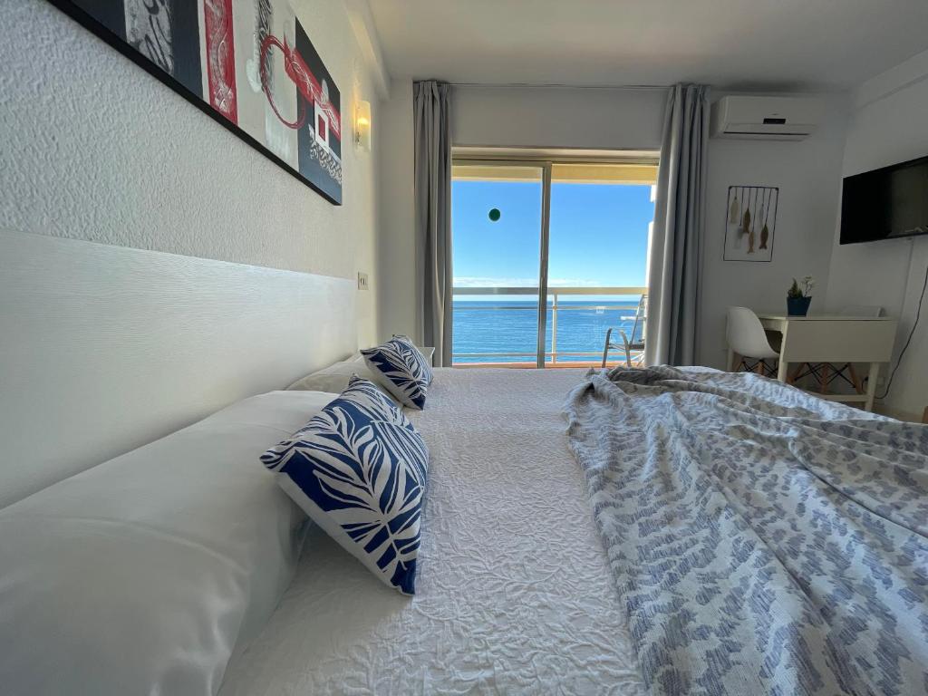 a bedroom with a bed with a view of the ocean at Apartahotel CHINASOL con Parking y Desayuno in Almuñécar