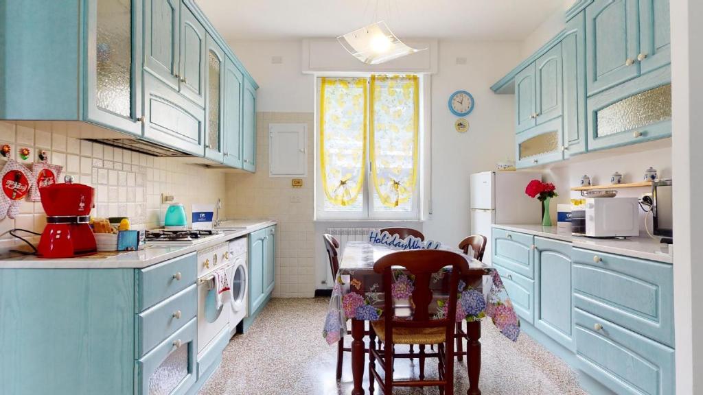 a kitchen with blue cabinets and a table with chairs at House Azzurra by Holiday World in Genova