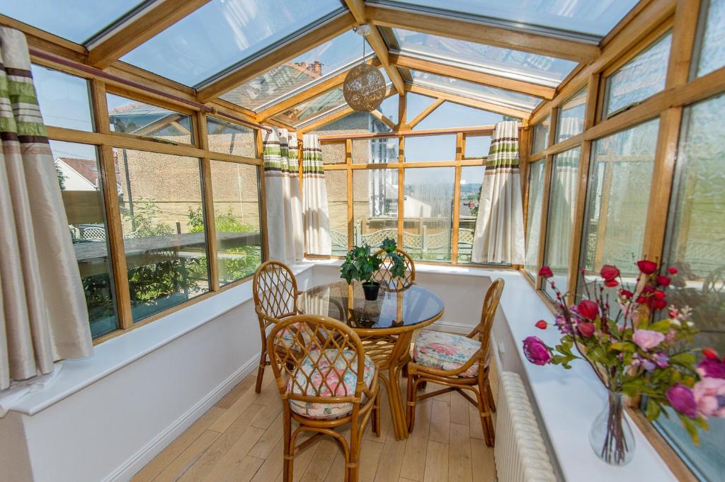 a conservatory with a table and chairs and windows at Sean's Pond in Shipley