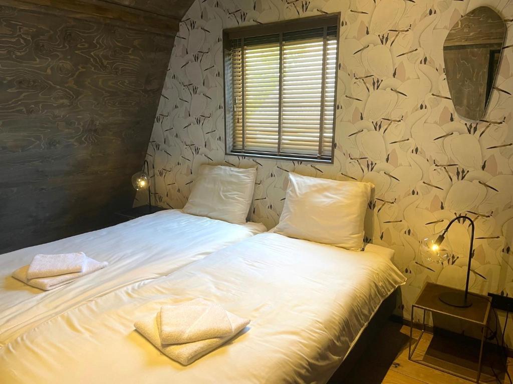 een slaapkamer met een bed met witte lakens bij Loft Heerehof in Schoorl