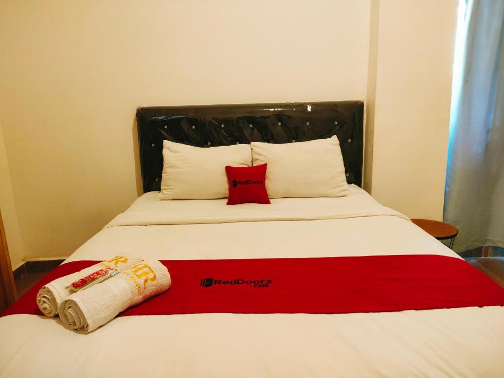een bed met een rode en witte deken en 2 kussens bij RedDoorz At Sukomanunggal Surabaya in Surabaya