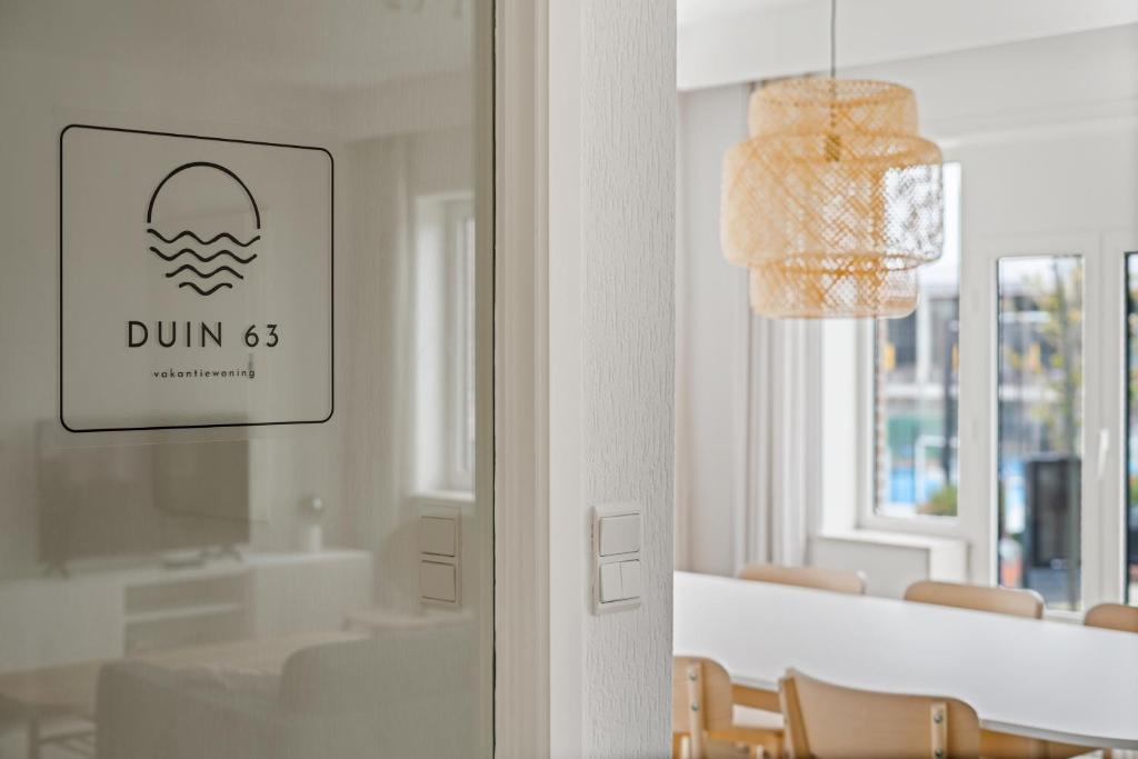 a dining room with a table and a sign on a door at - Duin 63 - Ruim 8 pers duplex app met terras in Koksijde