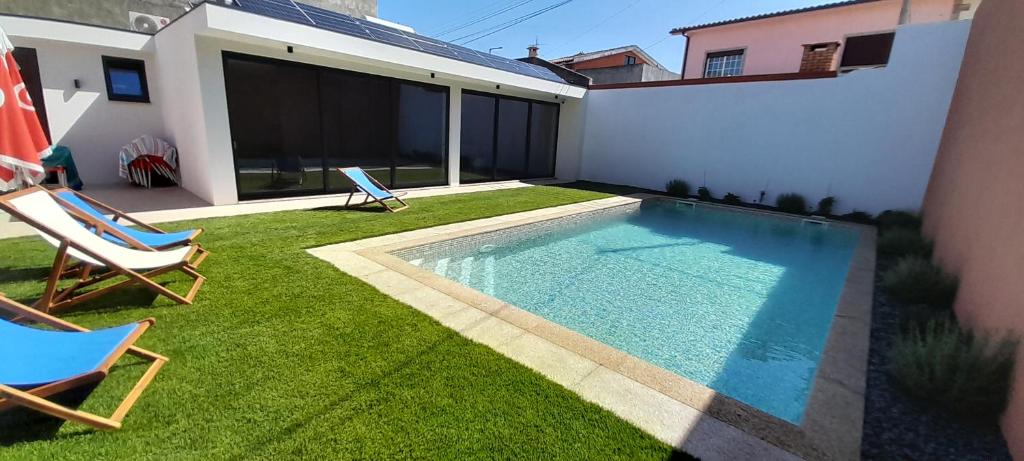 a backyard with a swimming pool and two lawn chairs at Sargaço Suíte Pool and Beach in Póvoa de Varzim