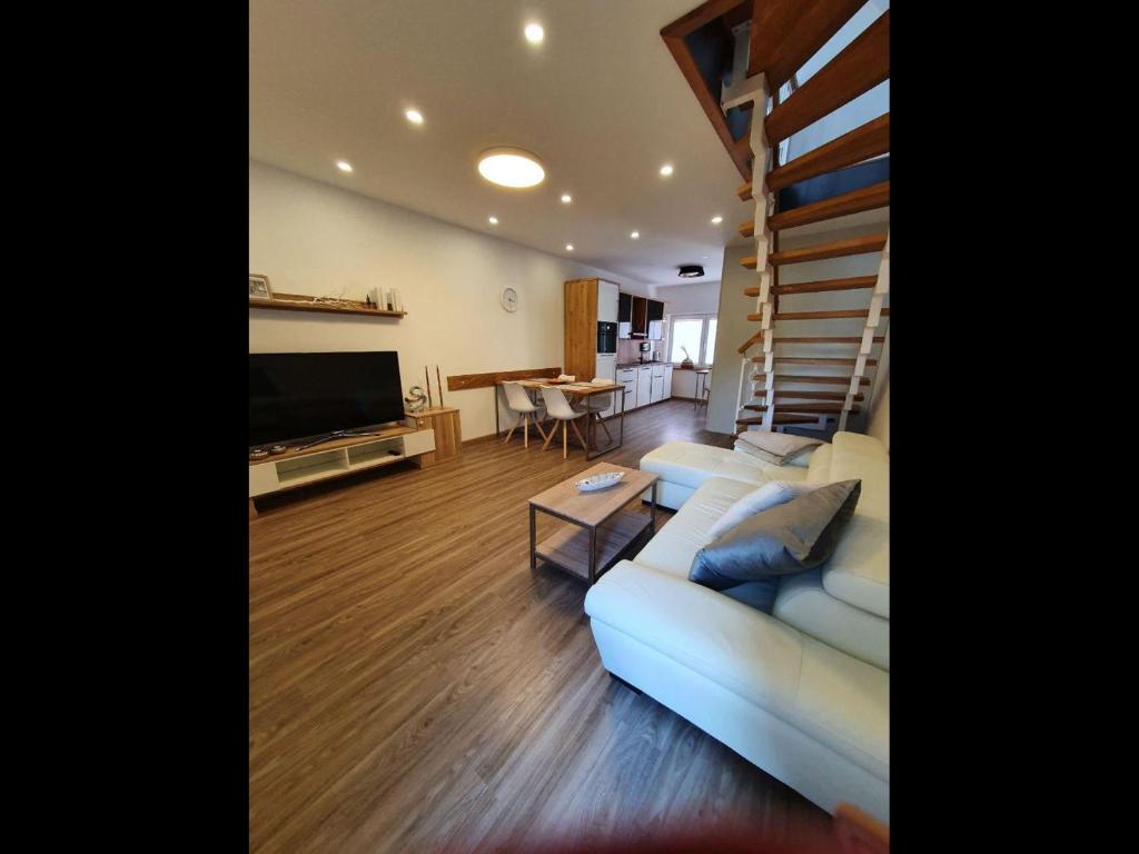 ein Wohnzimmer mit einer weißen Couch und einer Treppe in der Unterkunft NEU! Ferienhaus 54 Husum inkl Sauna in Husum