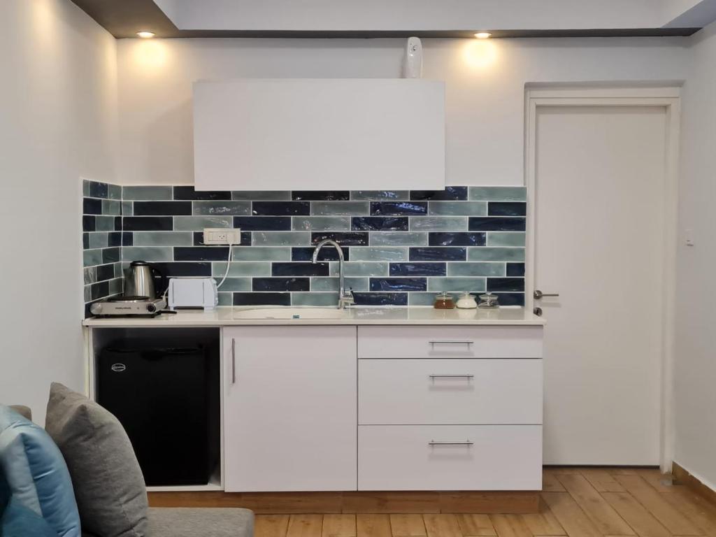 a kitchen with white cabinets and a brick wall at Suite4u in Eilat