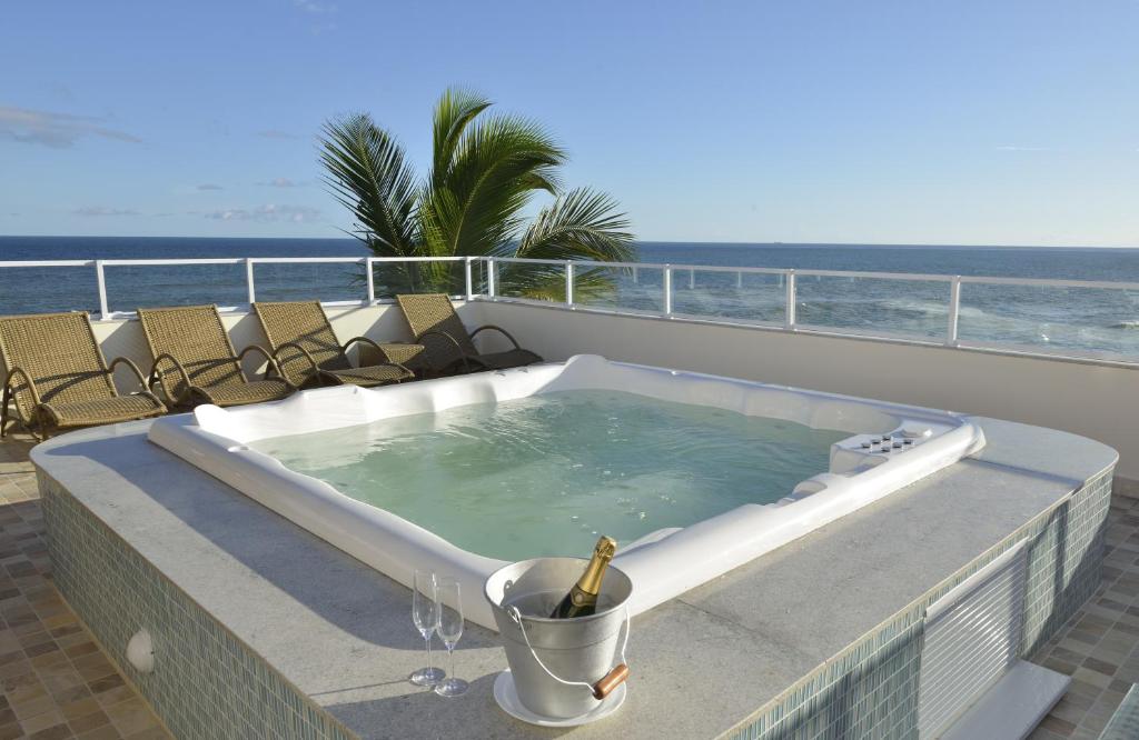 bañera de hidromasaje en un balcón con vistas al océano en el fondo en Rede Andrade Express en Salvador