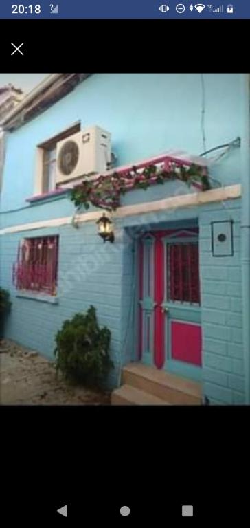 una casa azul con puerta roja y ventanas en Ayvalık Rum evi, en Ayvalık