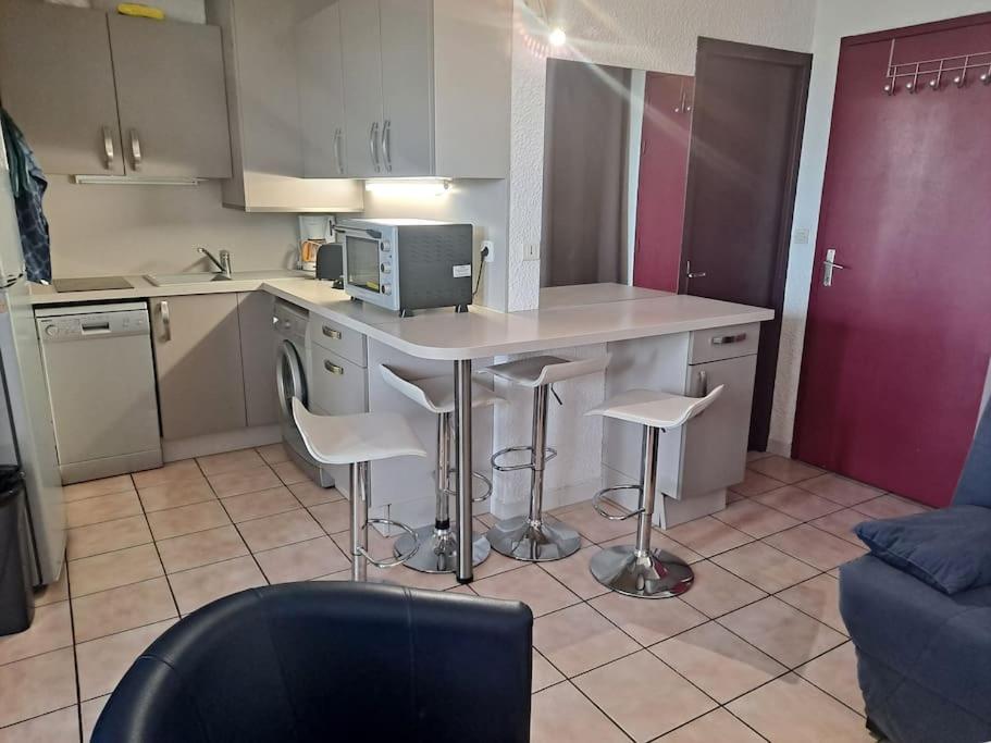 - une cuisine avec une table, des tabourets et un four micro-ondes dans l'établissement appartement le Florid Cap d'Agde, T2 , 4 pers, 200m plage, terrasse, au Cap d'Agde