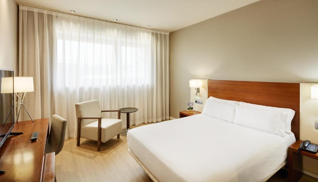 モンカダ・イ・レイシャクにあるセルコテル シウタット デ モンカダの大きなベッドとデスクが備わるホテルルームです。