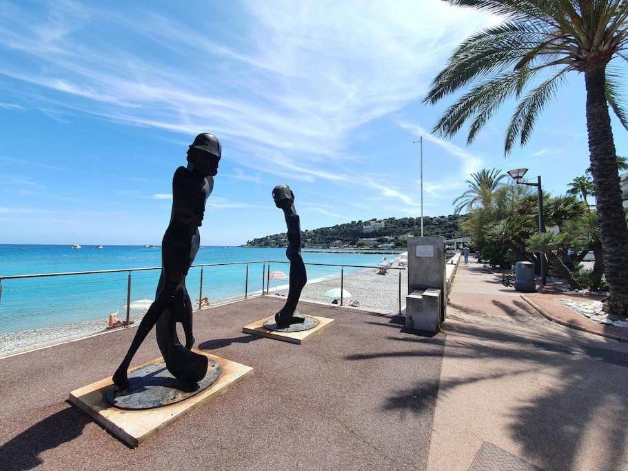two statues of people on a beach near the ocean at Roquebrune : Appartement 4 personnes proche de la plage (AV) in Roquebrune-Cap-Martin