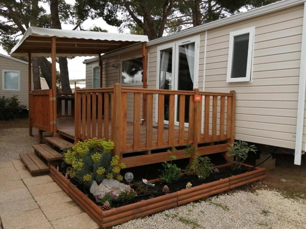 a house with a porch and a deck with plants at Mobil-home (Clim)- Camping Narbonne-Plage 4* - 011 in Narbonne-Plage