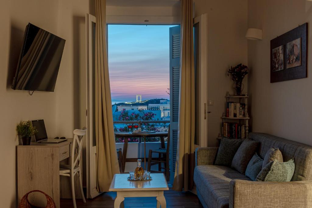 un soggiorno con divano, tavolo e finestra di Venetian Suites III a Naxos Chora