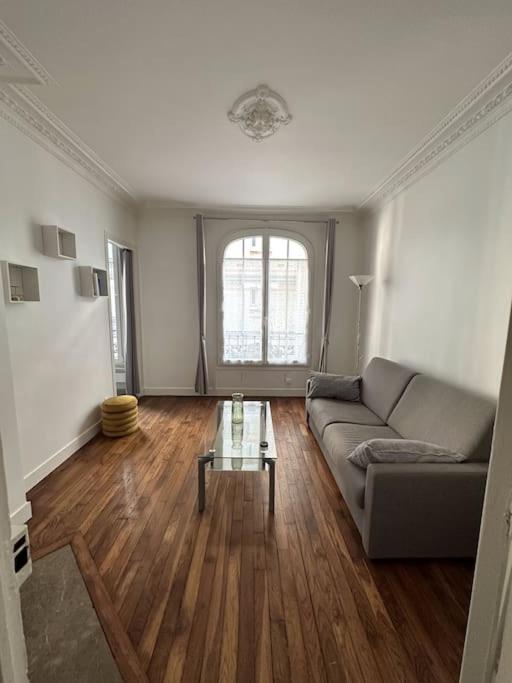 Charmant Appartement Parisien في باريس: غرفة معيشة مع أريكة وطاولة