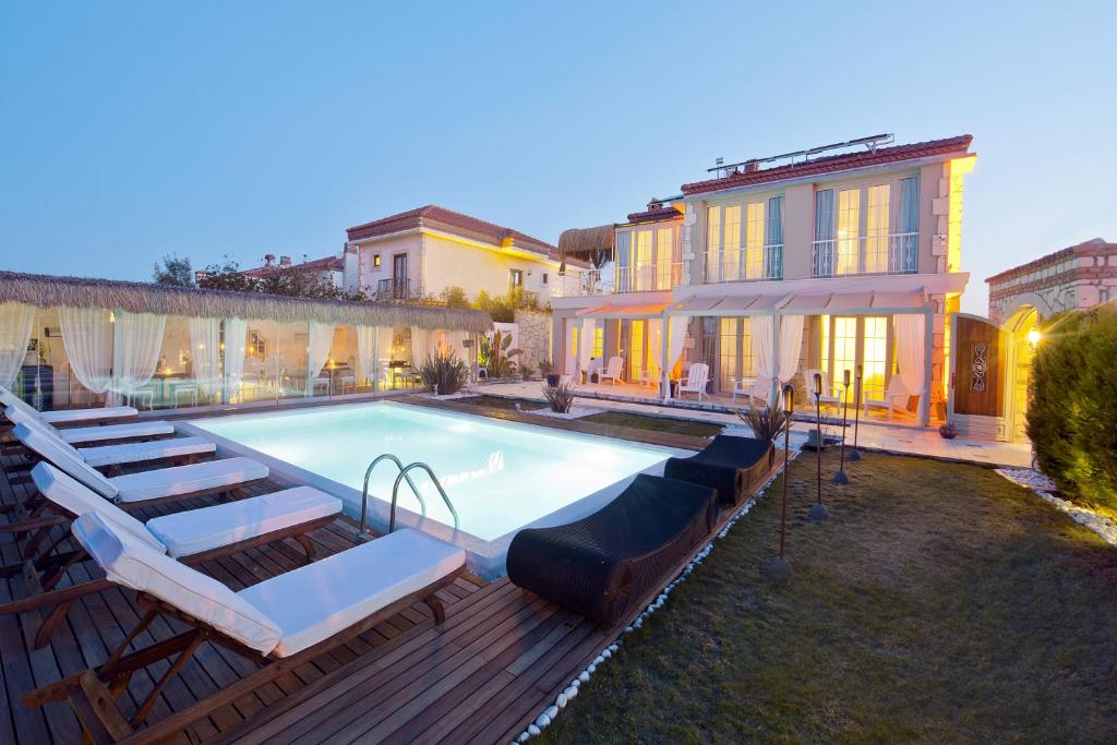 a swimming pool with lounge chairs and a house at Sade Alacati Hotel in Alacati