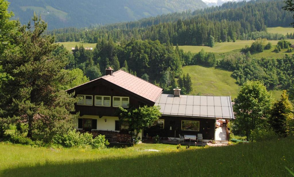 a house in the middle of a field with trees at Ferienhaus Riedlsperger in Fieberbrunn