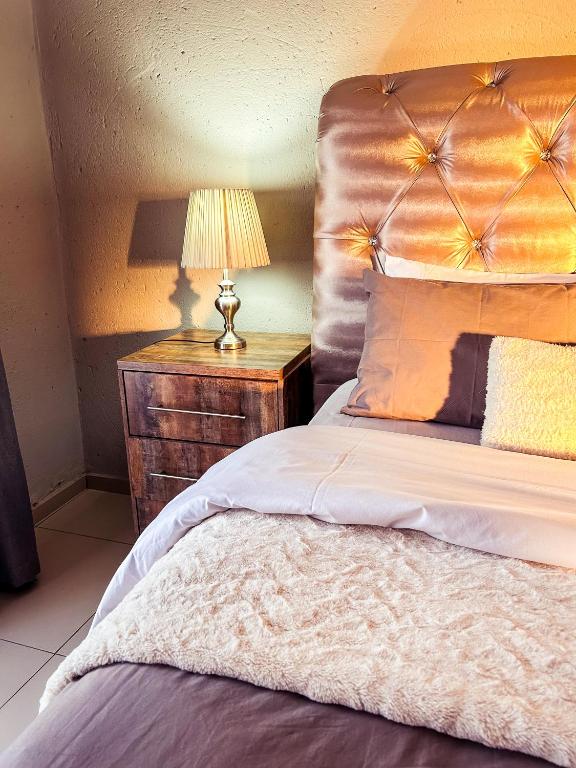 a bedroom with a bed with a lamp on a night stand at Mjejane Debs guest house in Hectorspruit