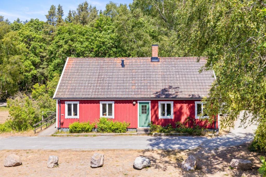 Raftarp - Country side cottage in the woods في Sjöbo: منزل احمر بسقف رمادي