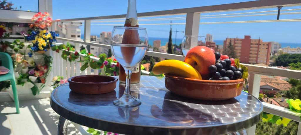 a table with a glass of wine and a bowl of fruit at Acuario shared flat piso compartido est partagé الشقة مشتركة in Benalmádena