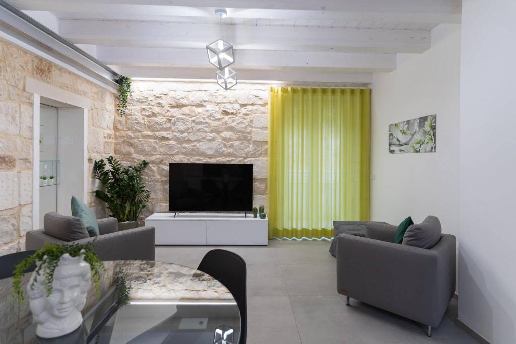 uma sala de estar com uma televisão e uma mesa e cadeiras em Lovely Modern Apartment em Modica