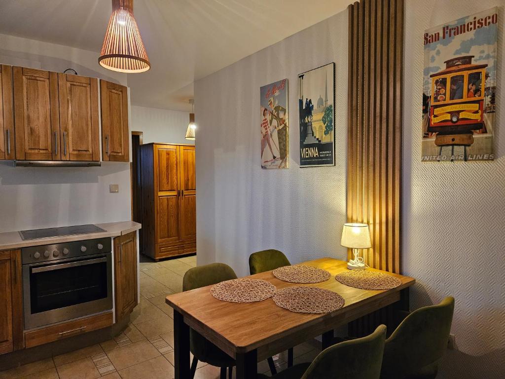 cocina con mesa de madera y sillas verdes en Apartament Iskra, en Zakopane