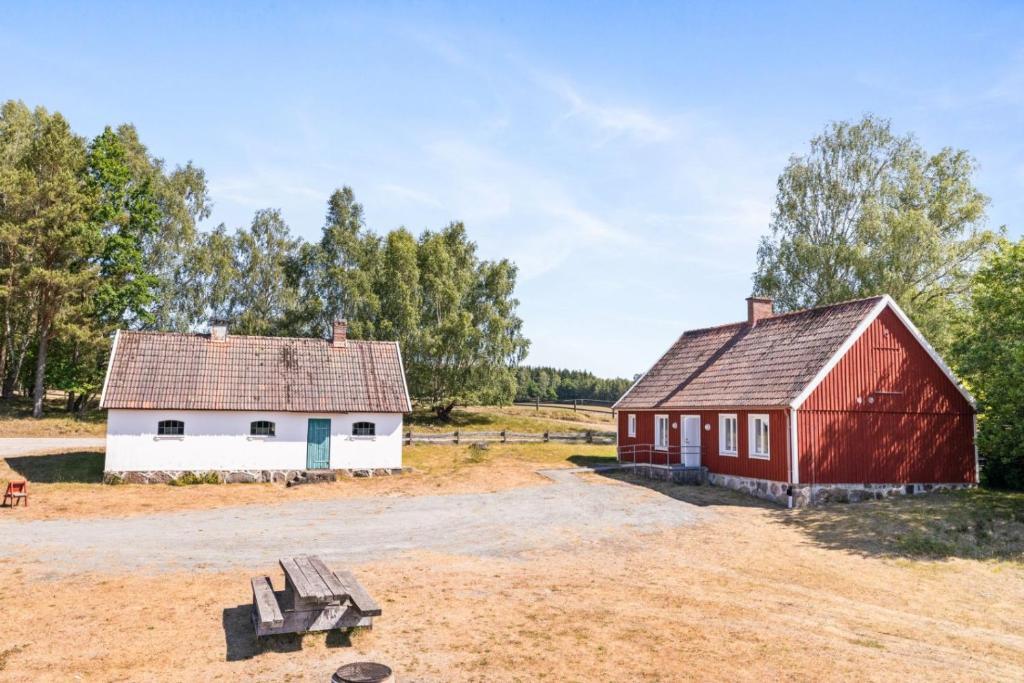 um celeiro vermelho e um edifício branco num campo em Jocksborg - Country side cottage in the woods em Sjöbo