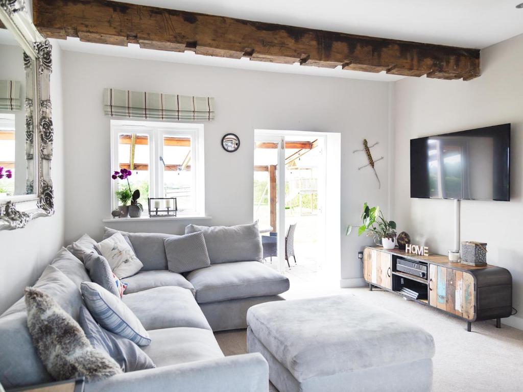 a living room with a couch and a tv at Pass the Keys Stunning Cheshire Barn with HotTub in Sandbach