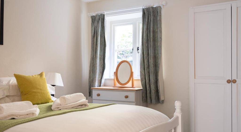 a bedroom with a bed with a mirror and a window at Coniston in Sawrey