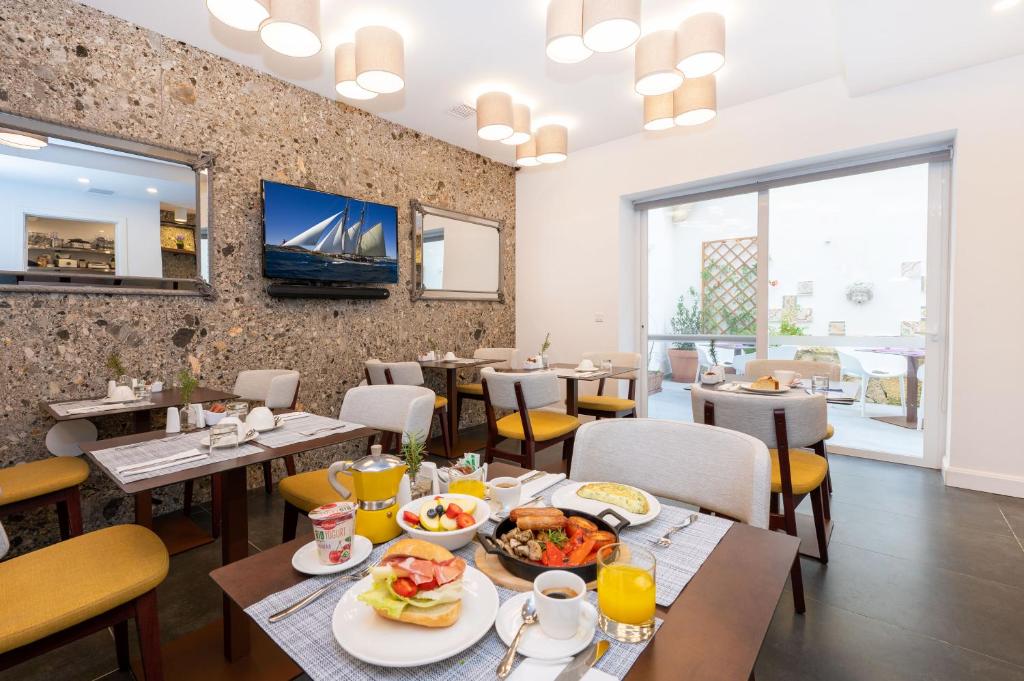 Battistini Boutique Living Hotel and Spa, Victoria, Gozo في فيكتوريا: مطعم عليه طاولات وكراسي عليها طعام