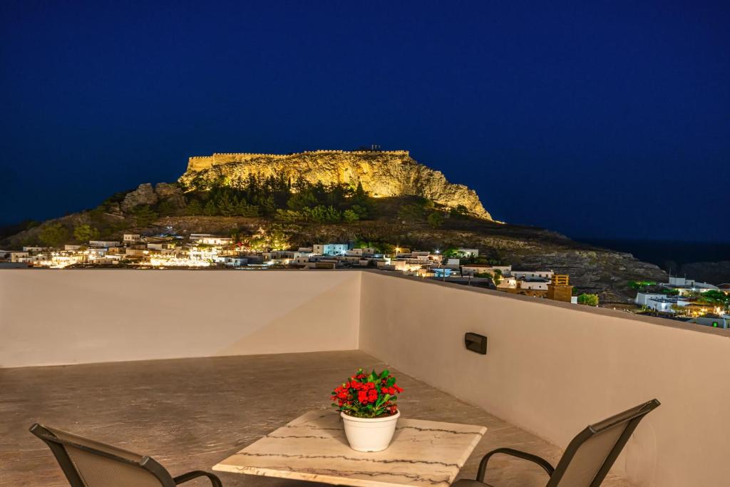 a table and chairs with a mountain in the background at Villa Danae - Lindos in Líndos