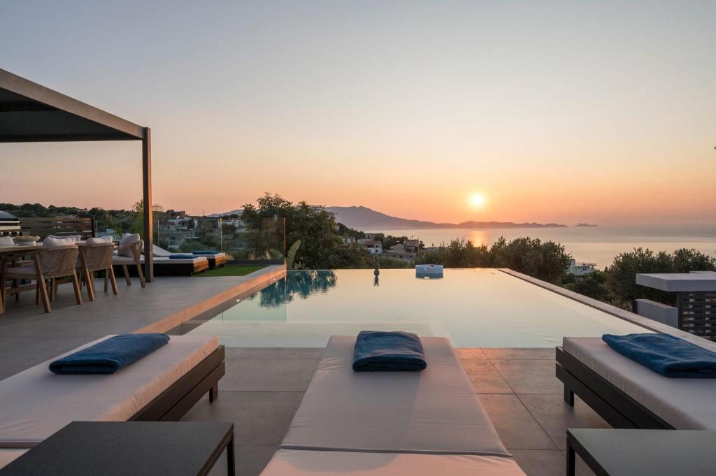 une piscine avec vue sur le coucher du soleil en arrière-plan dans l'établissement Villa Ekphrasis with sea view and jacuzzi, à Ravdhoúkha