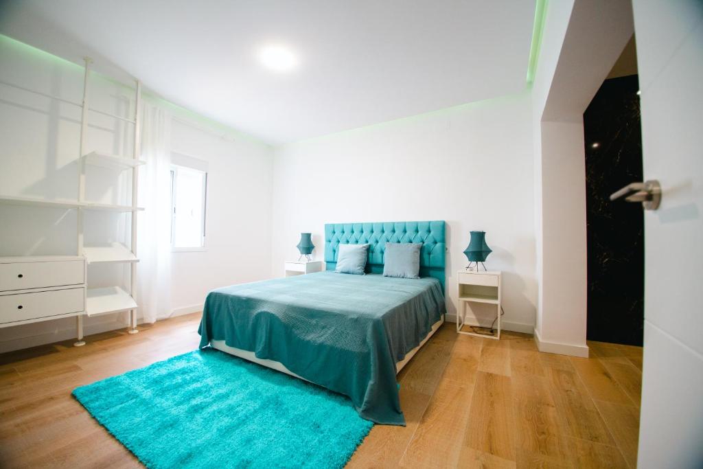 a bedroom with a blue bed and a blue rug at LUZ DE PATIOS in Huelva