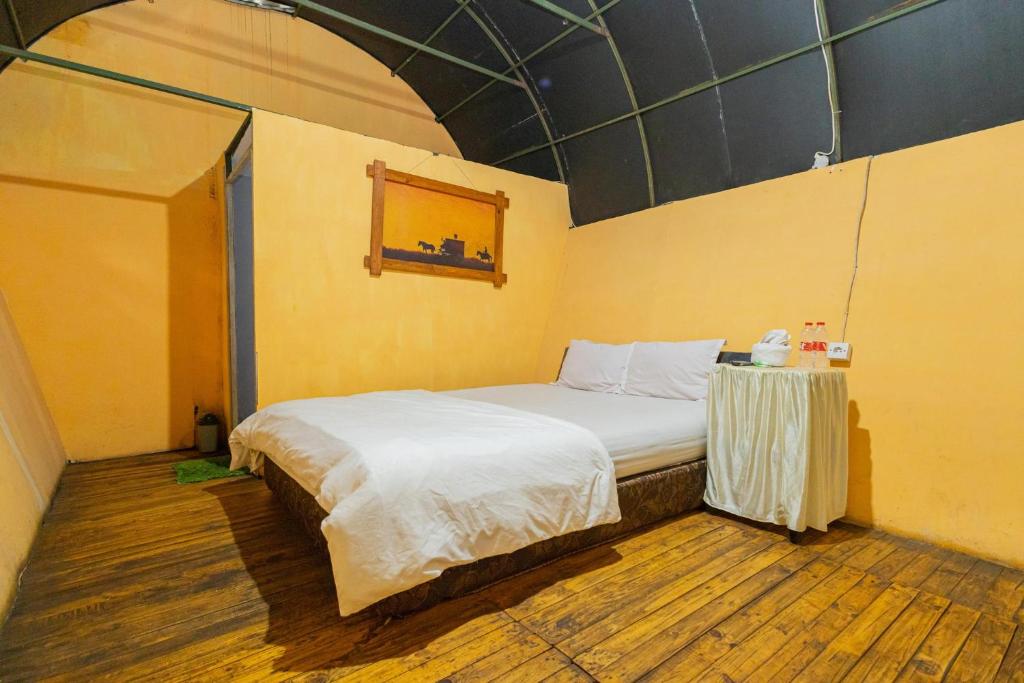 a bedroom with a bed and a table in it at Chikar Glamping At Wisata Coban Talun Mitra RedDoorz in Junggo