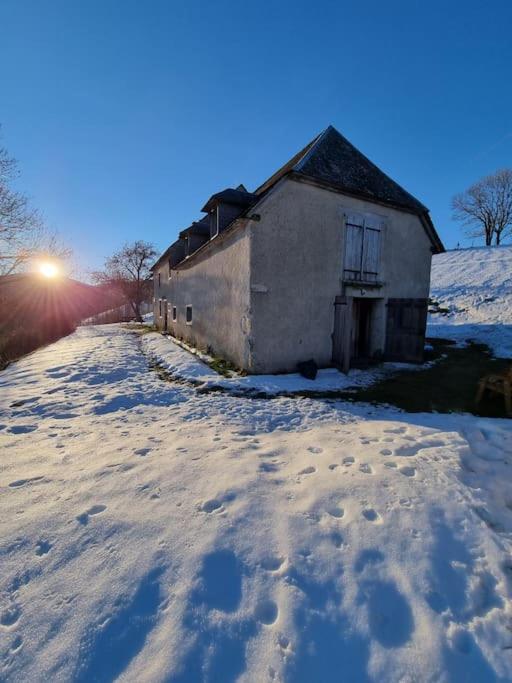 une vieille maison sous la neige avec le soleil en arrière-plan dans l'établissement Grange authentique rénovée, à Campan