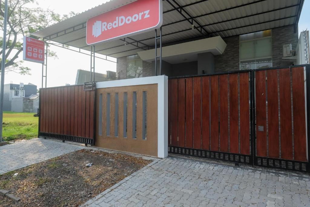 un edificio con una puerta roja y un cartel en él en RedDoorz near Kawasan Bandara Ahmad Yani Semarang 2 en Kalibanteng-kidul