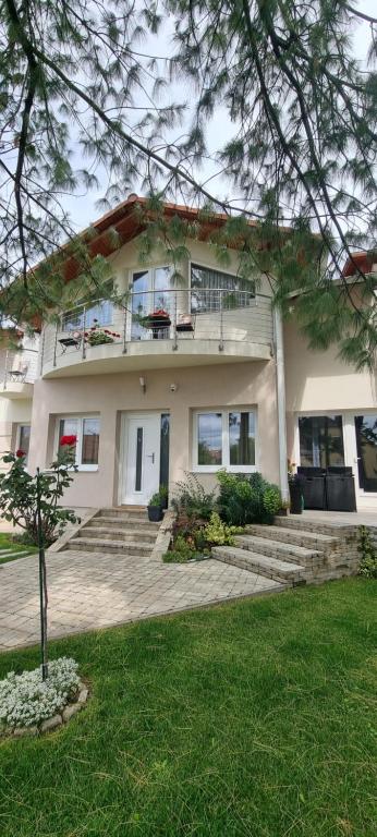 a large white house with stairs in a yard at City Center apartman in Siófok