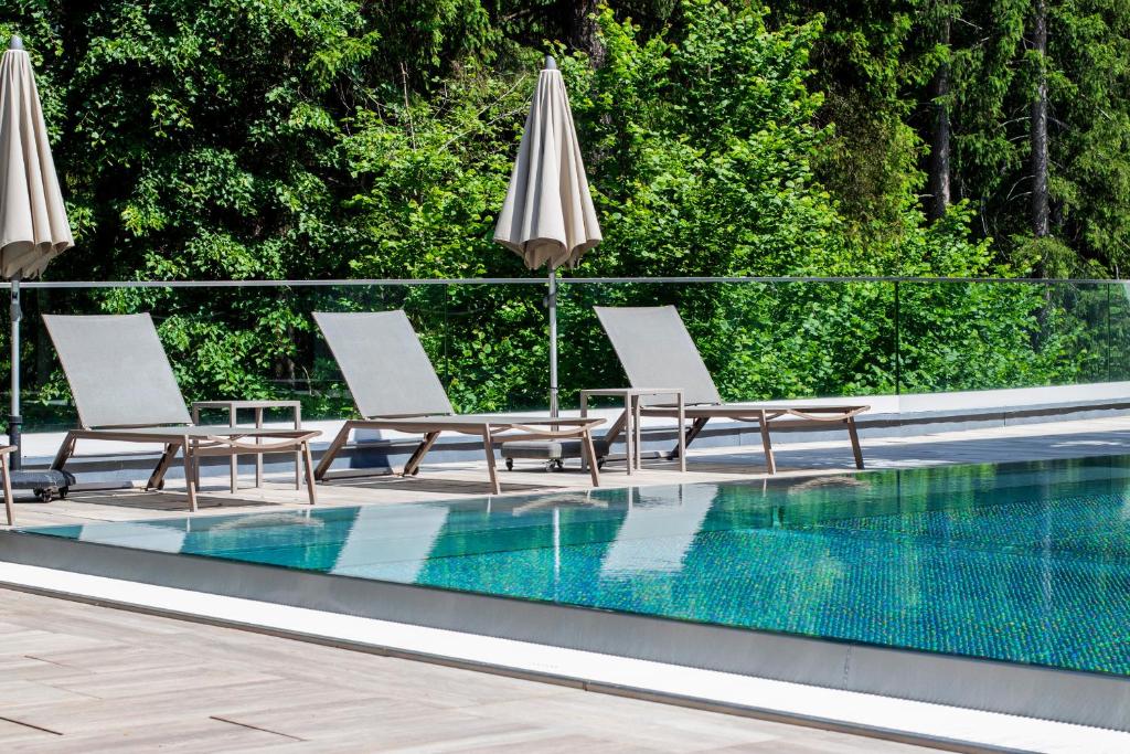 a group of chairs and umbrellas next to a swimming pool at Aktivhotel Waldhof in Oetz