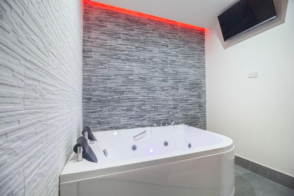 a bath tub in a bathroom with a brick wall at Royal Playa Suite and Apartament -private parking- self chek out in Catania