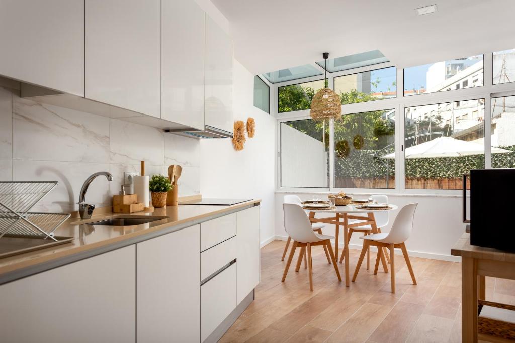 a kitchen with white cabinets and a table with chairs at Lisbon Zoo House III in Lisbon