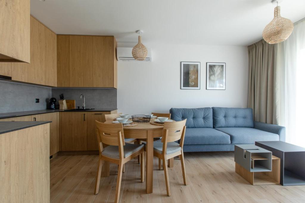 cocina y sala de estar con mesa y sofá azul en Apartament Perłowy by Major Domus Club, en Dziwnów