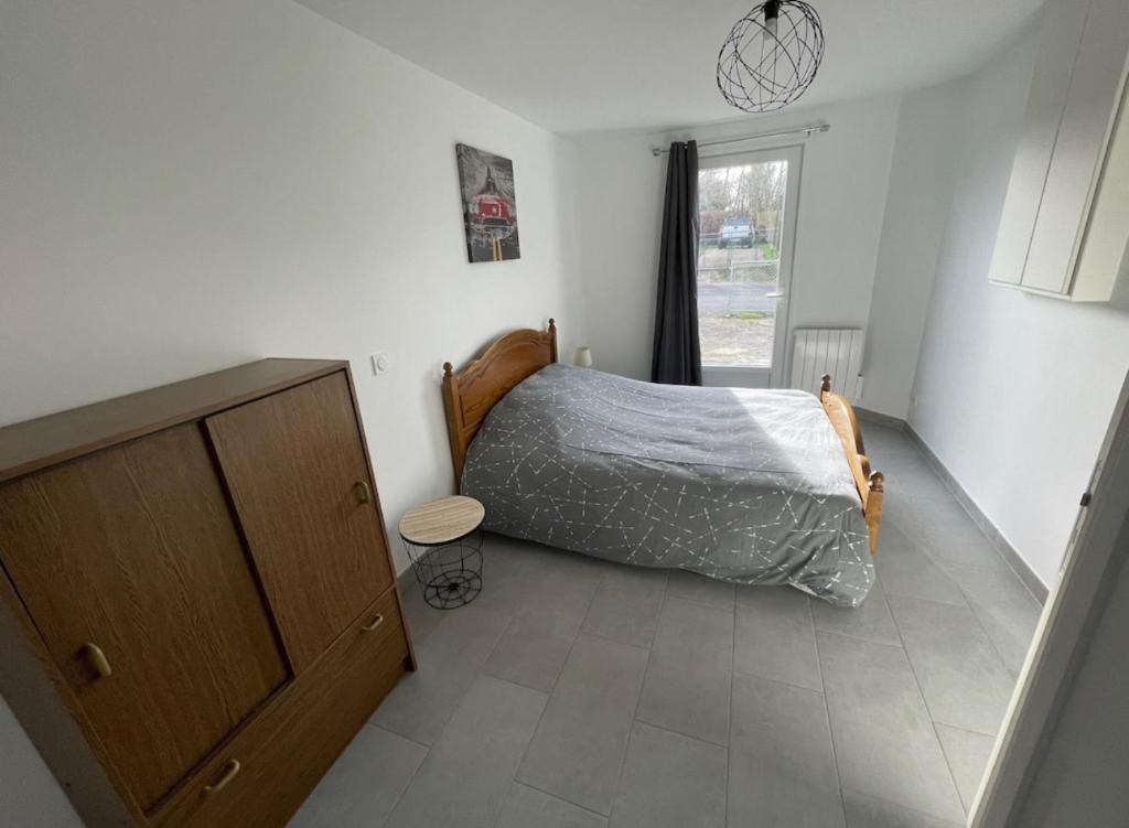 ein Schlafzimmer mit einem Bett, einer Kommode und einem Fenster in der Unterkunft Gîte Le Rhodo in Thil-Manneville