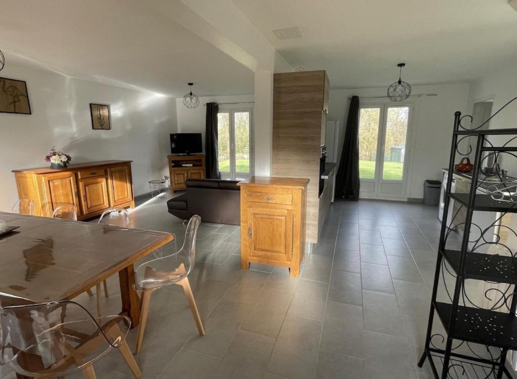 eine Küche und ein Wohnzimmer mit einem Tisch und Stühlen in der Unterkunft Gîte Le Rhodo in Thil-Manneville