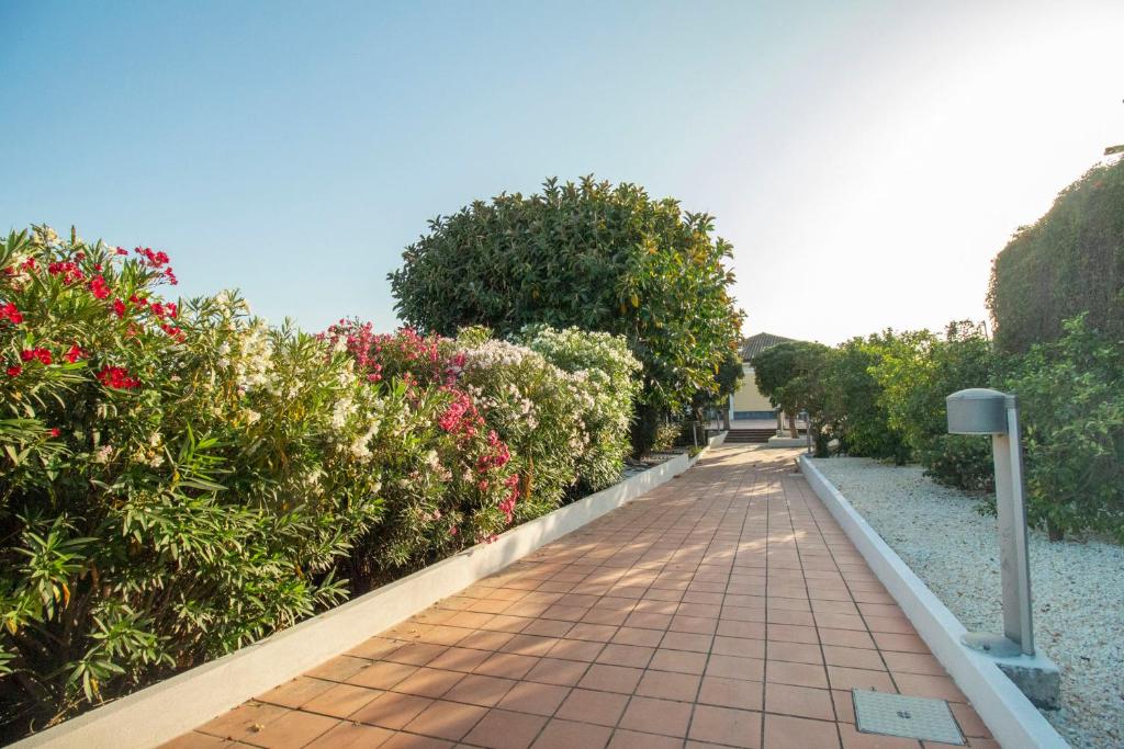 una pasarela a través de un jardín con flores y arbustos en Royal Playa Suite and Apartament -private parking- en Catania