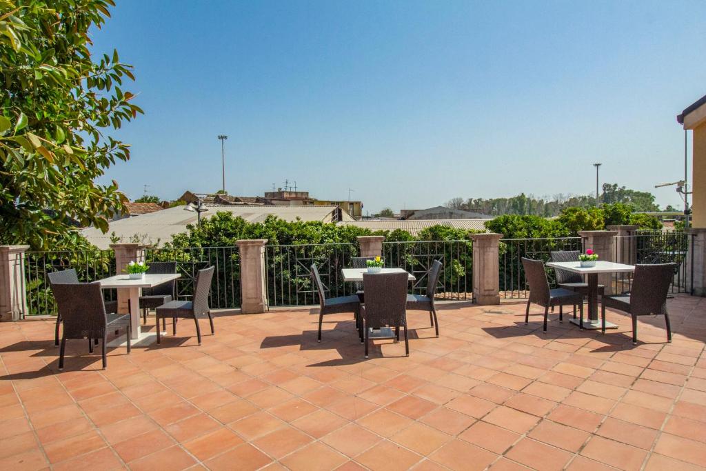 a patio with tables and chairs in front of a fence at Royal Playa Suite and Apartament -private parking- self chek out in Catania