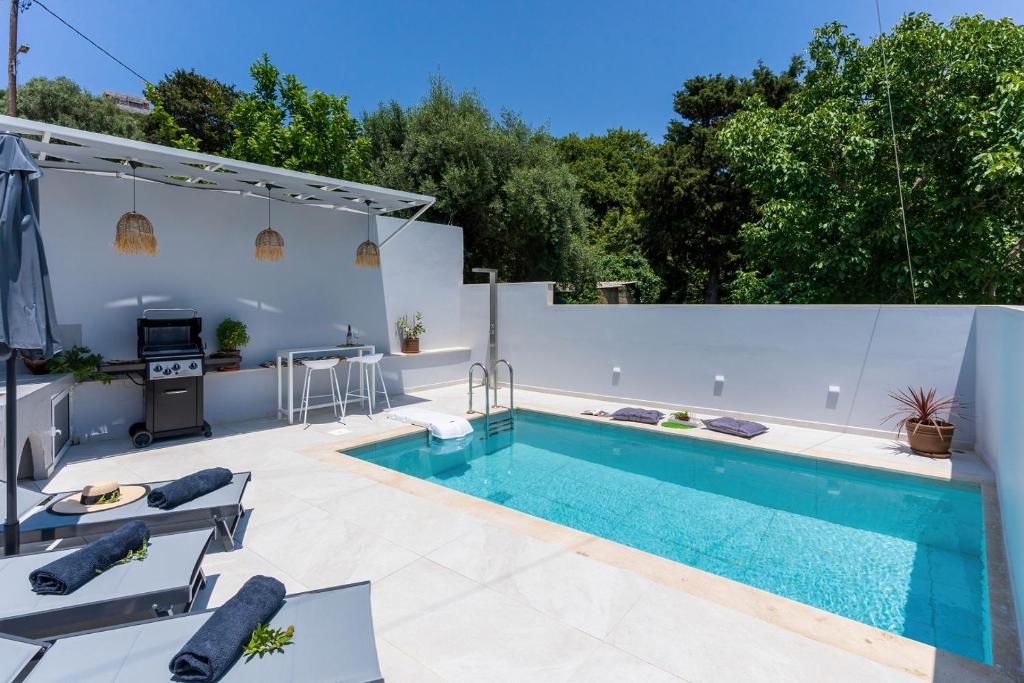 a swimming pool in a backyard with a white fence at Villa Venetia with Jacuzzi in Lambiní