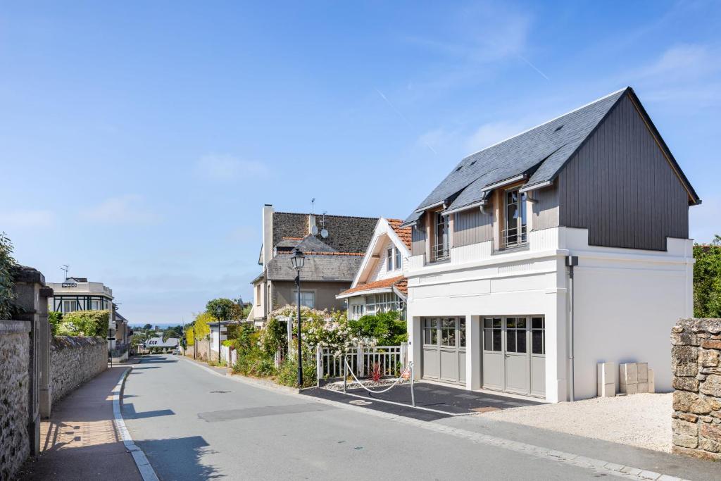 une maison blanche avec un toit noir dans une rue dans l'établissement La Fleur du Moulin - Charmante maison avec jardin proche plage, à Saint-Briac-sur-Mer