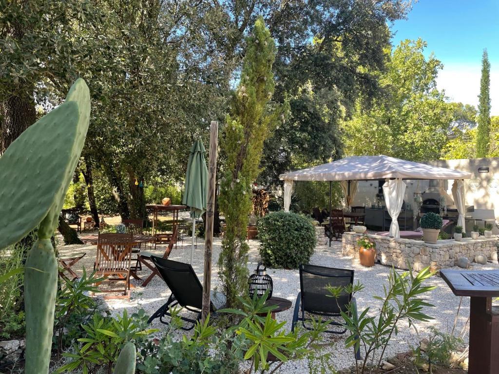 une terrasse avec une table, des chaises et un parasol dans l'établissement Les Jardins d'Holi appartement proche Uzès, à Garrigues-et-Sainte-Eulalie
